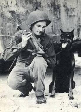 Soldier crouching next to his dog.